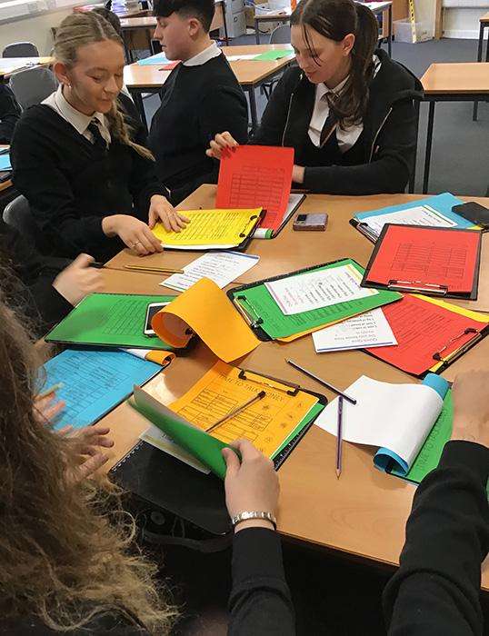 Coatbridge students sitting around a table with exercise books on it